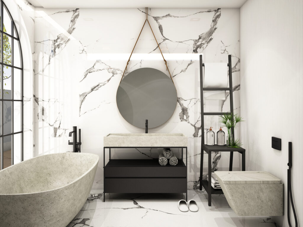 Bagno con vasca da bagno bianca sulla sinistra, wc bianco sulla destra, lavabo bianco con specchio tondo e parete di marmo bianco e nero